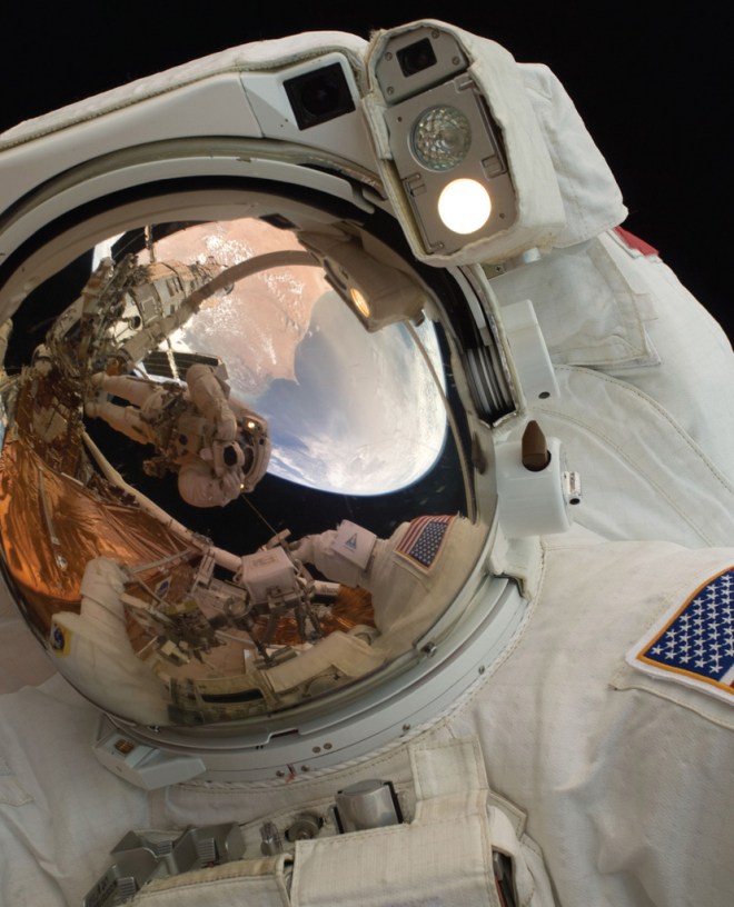 A close-up of Astronaut John Grunsfeld shows the reflection of Astronaut Andrew Feustel, perched on the robotic arm and taking the photo. The pair teamed together on three of the five spacewalks during Servicing Mission 4 in May 2009.  